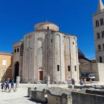 an old building with two towers and people walking around it