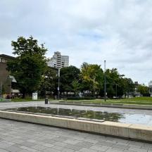 ein Brunnen in einem Park mit Bäumen und Gebäuden