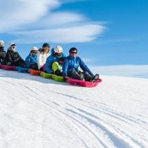 un gruppo di persone che scendono su una slitta lungo un pendio innevato