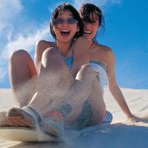 zwei Mädchen sitzen im Sand am Strand