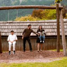 a family is sitting on a wooden swing