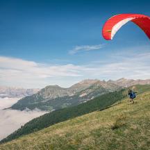 eine Person, die auf einem Berggipfel einen Drachen steigen lässt