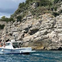 a white boat in the water near a rocky cliff