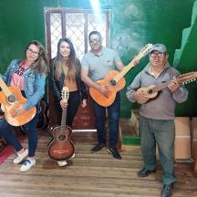 група людей, що стоять у кімнаті з гітарами в руках