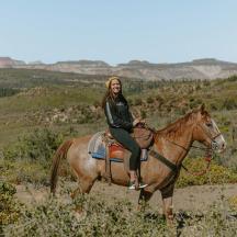 a woman riding on a horse in a field