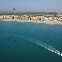 una barca in acqua con un aquilone che vola sopra una spiaggia