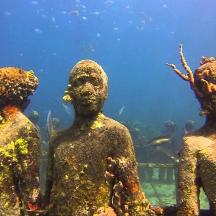 eine Gruppe von skulpturierten Menschen steht vor einem Aquarium