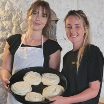 two women holding a tray of cupcakes
