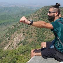 a man with a backpack sitting on top of a mountain