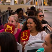 a group of people sitting in a crowd with big smiles signs