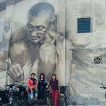 a group of people standing in front of a mural of a man