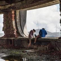 a painting of two people sitting on a bridge