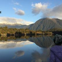 a woman sitting in front of a reflection of a mountain
