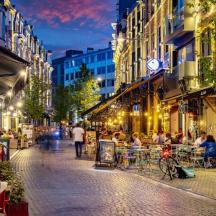 eine Stadtstraße bei Nacht mit Menschen, die an Tischen sitzen