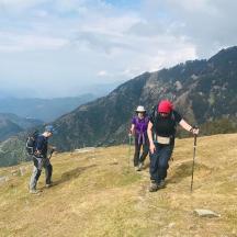 a group of three people walking on top of a mountain