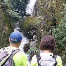 two people are looking at a waterfall on a mountain