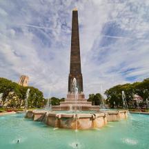 en fontene med en høy obelisk i en park