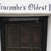 a sign above a wooden door on a white building