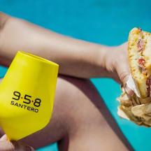 a person holding a hot dog and a yellow cup