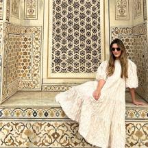 a woman in a white dress sitting on a wall