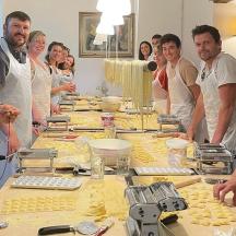 eine Gruppe von Menschen steht mit Essen um einen Tisch herum
