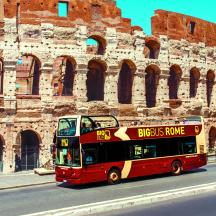 a red double decker bus driving past a building