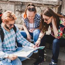 tres persones assegudes en unes escales mirant un mapa