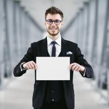un homme en costume tenant une pancarte blanche