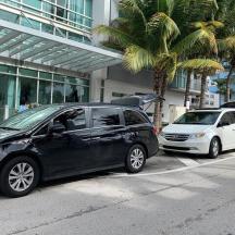 dua buah kereta diletakkan di hadapan sebuah bangunan dengan pokok palma
