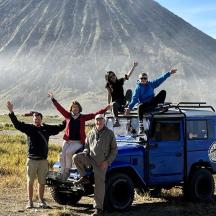 un grup de persones assegudes a sobre d'un jeep davant d'una muntanya