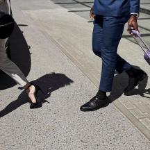 two people walking down the street pulling a purple suitcase