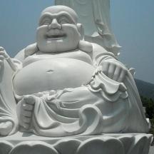 a large white statue of a monk with a purse