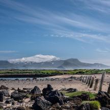 a fence on a beach with mountains in the background