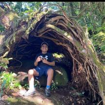 a man sitting in a tree root shaped cave