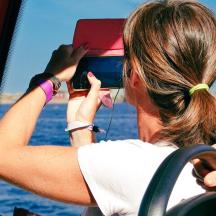a woman taking a picture of the ocean with her cell phone