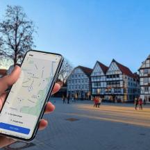 eine Person, die in einer Stadt ein Mobiltelefon hält