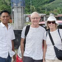 two men and a woman standing next to a car