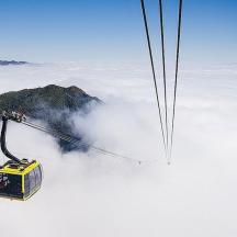a cable car flying over a mountain with clouds