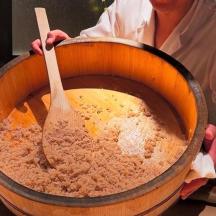 a person holding a bowl of food with a wooden spoon