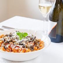 eine Schüssel Pasta neben einer Flasche Wein