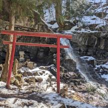 a red torii gate in the snow next to a waterfall