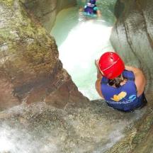 eine Frau klettert einen Felsen in einem Wasserfall hinauf