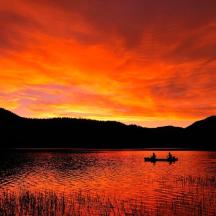 to personer i en båt på en innsjø ved solnedgang