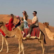 a group of people riding on camels in the desert