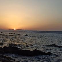 a sunset on a beach with rocks in the water