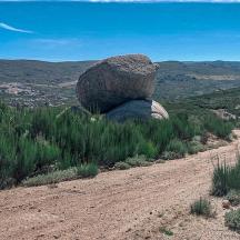 a rock sitting on the side of a dirt road