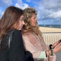 to kvinder står på en strandpromenade og kigger på en mobiltelefon