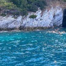 un groupe de personnes nageant dans l'eau près d'une grotte