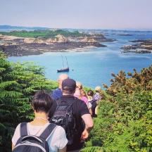 a group of people walking on a trail looking at the ocean