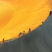 a group of people standing on a sand dune